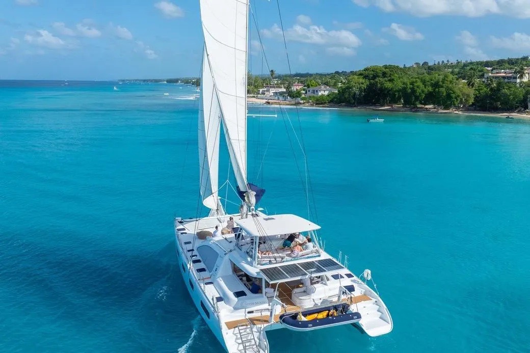 The yacht fuente resting on clear turquoise water beside a green coastline